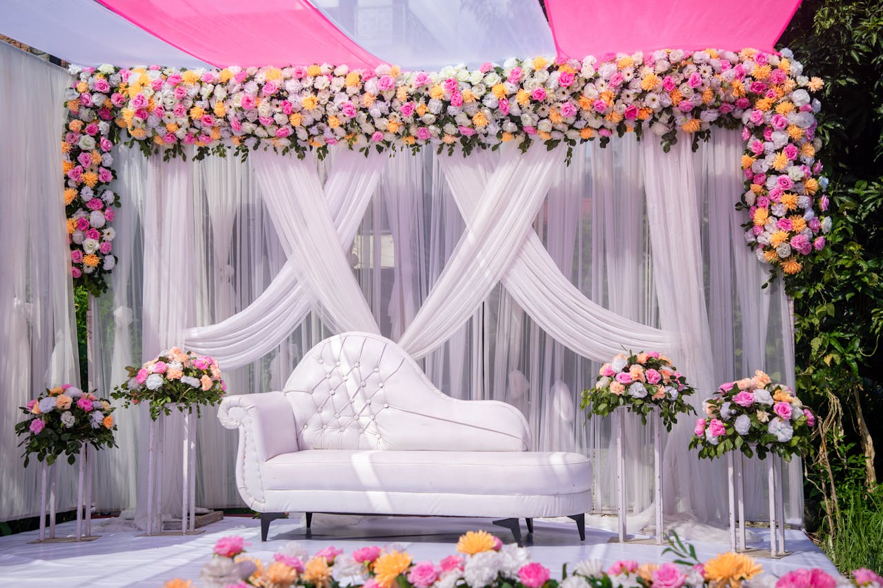 hero-img-01 Luxurious wedding stage setup decorated with vibrant floral arrangements and a white sofa, perfect for celebrations.