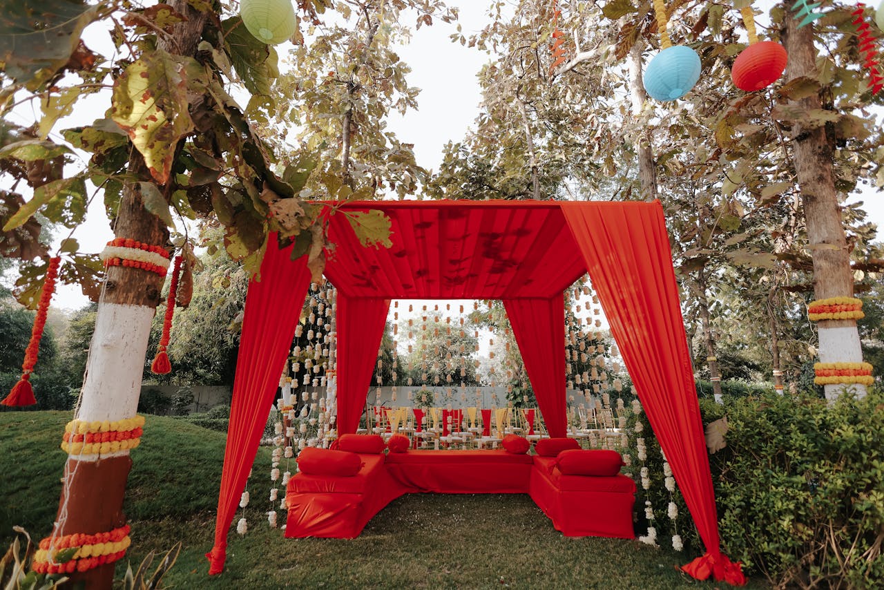hero-img-02 Beautiful outdoor wedding setup with red canopy, colorful lanterns, and floral decorations.